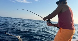 Fishing tours Malta: anglers on a traditional Maltese boat enjoying a sunset fishing trip in calm Mediterranean waters