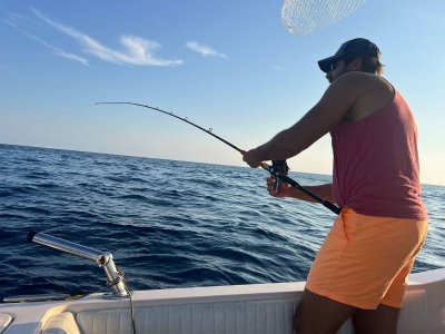 Fishing tours Malta: anglers on a traditional Maltese boat enjoying a sunset fishing trip in calm Mediterranean waters