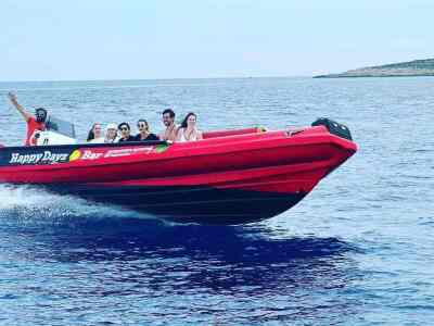 Passengers aboard a tour speedboat departing Valletta at sunset on a Malta harbour cruise