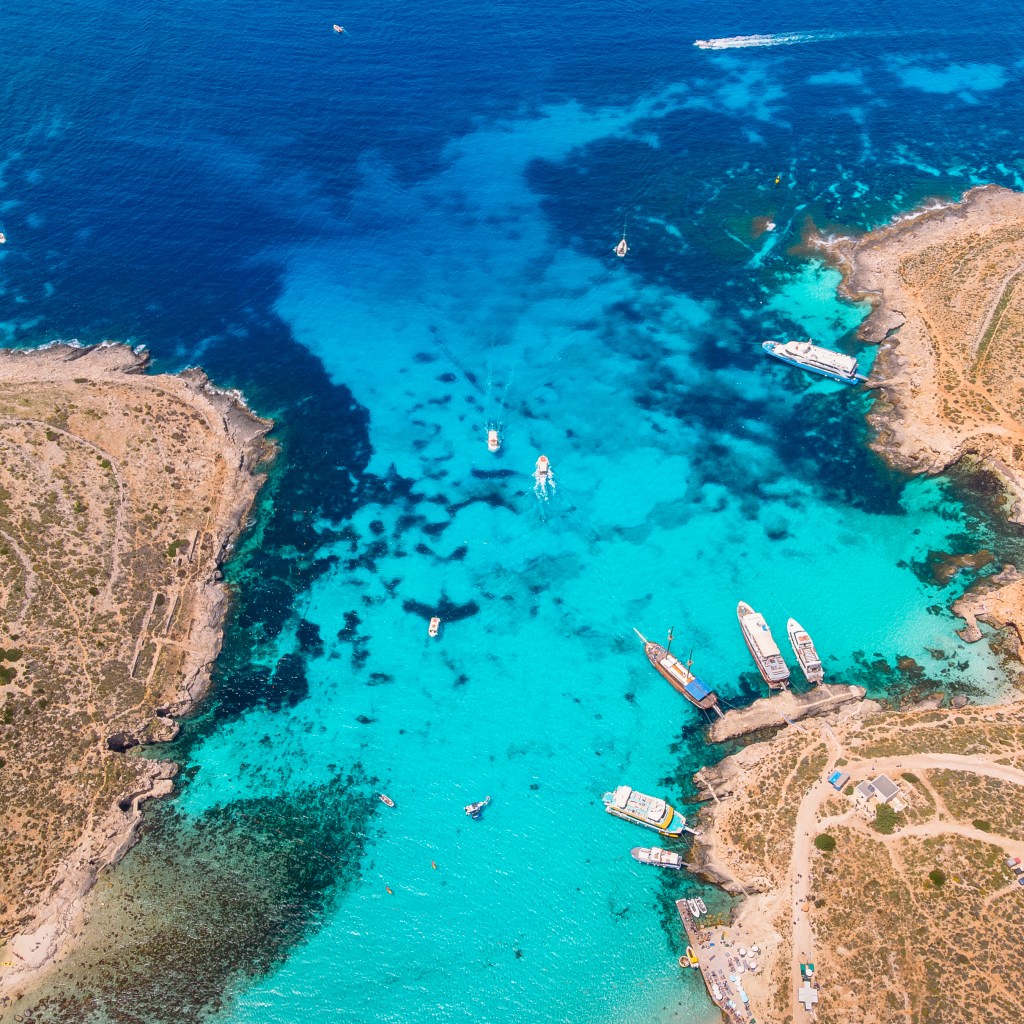 Several boats docked in the shallow turquoise waters of Comino’s Blue Lagoon