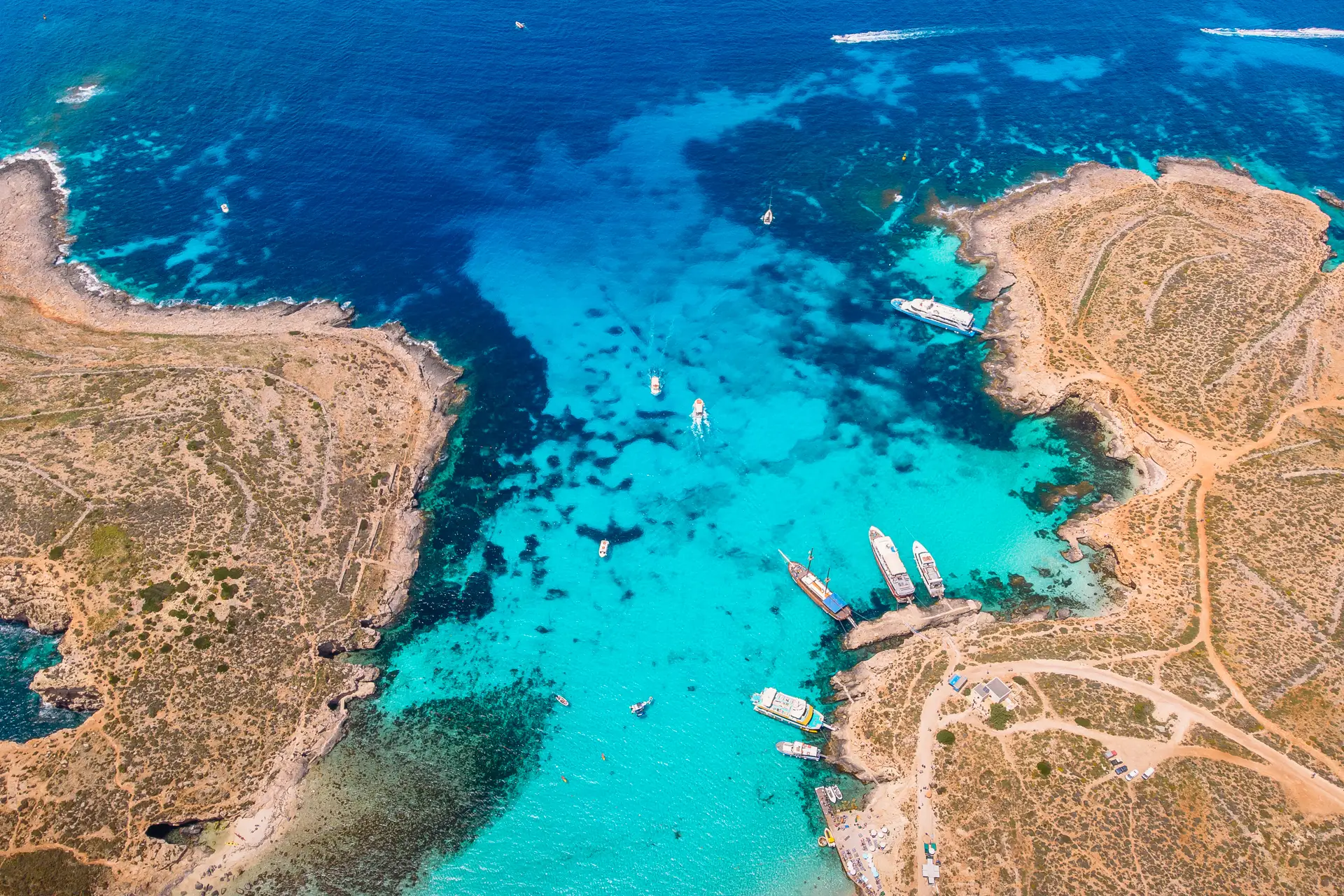 Several boats docked in the shallow turquoise waters of Comino’s Blue Lagoon