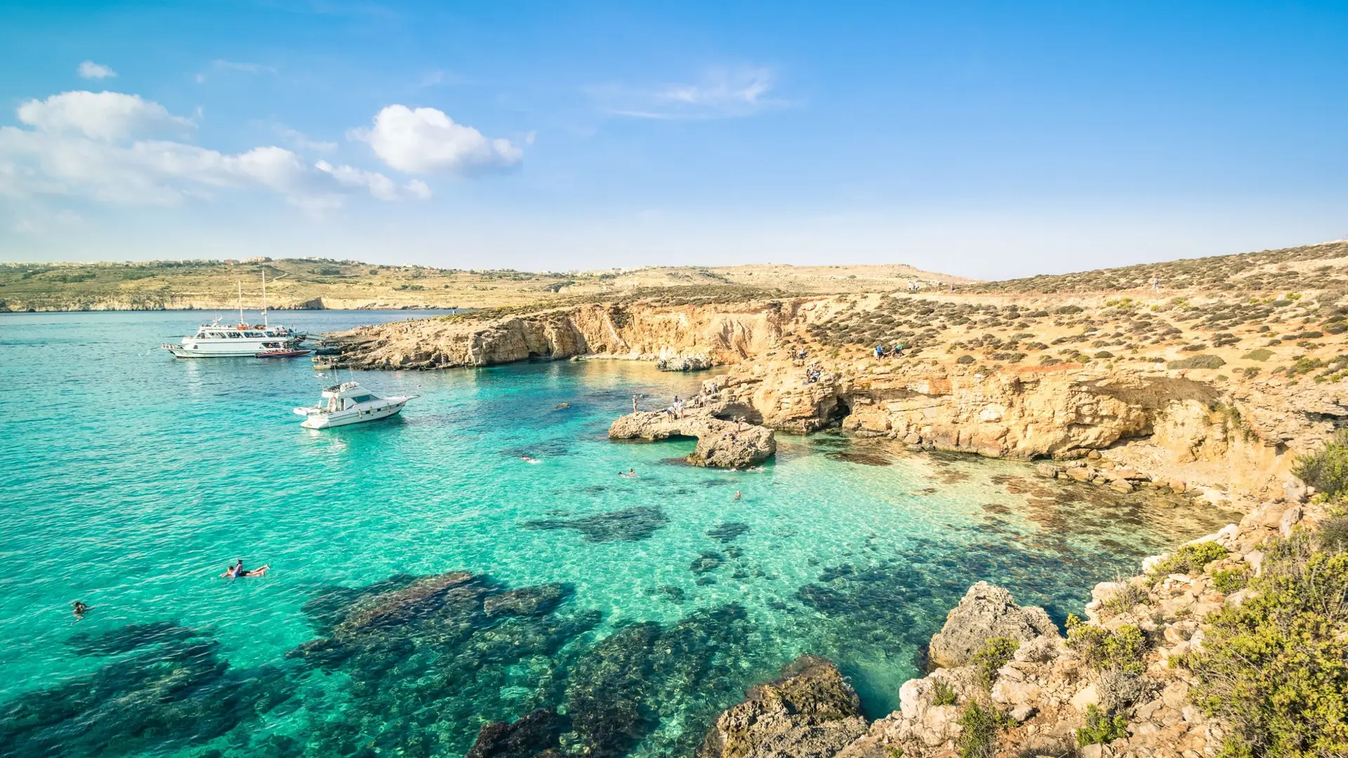 Malta Blue Lagoon turquoise water: luxury yacht returning from a day in the famous crystal-clear lagoon at dusk