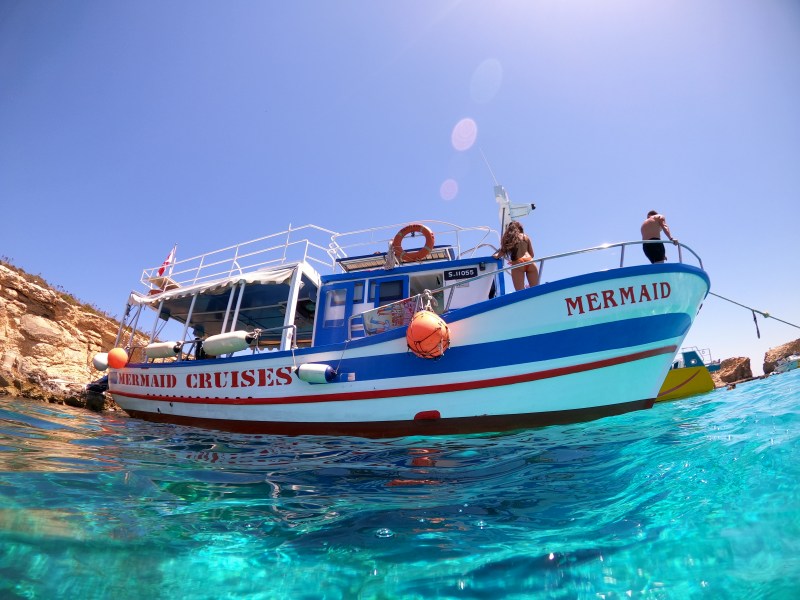 Comino boat tours and Blue Lagoon boat tours: half-day traditional maltese boat cruise packed with guests heading to Malta’s turquoise waters